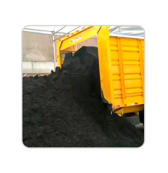 Carreta amarela descarregando composto orgânico